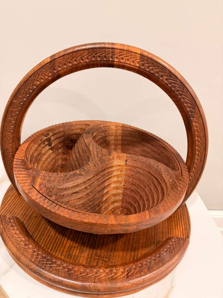 Stack of three wooden bowls with intricate carvings on a beige background