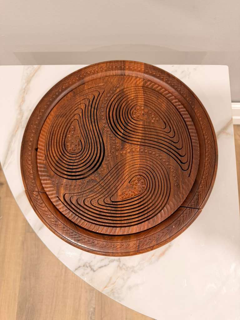 Wooden cutting board with decorative carvings on a marble surface
