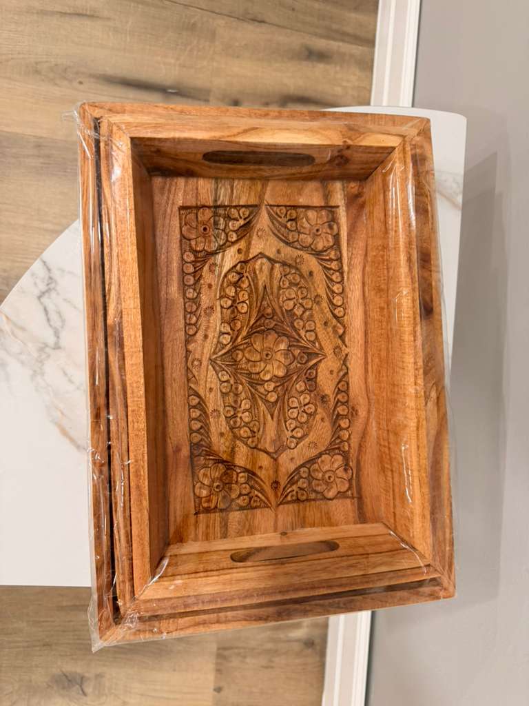 Wooden tray with intricate carvings on a marble surface