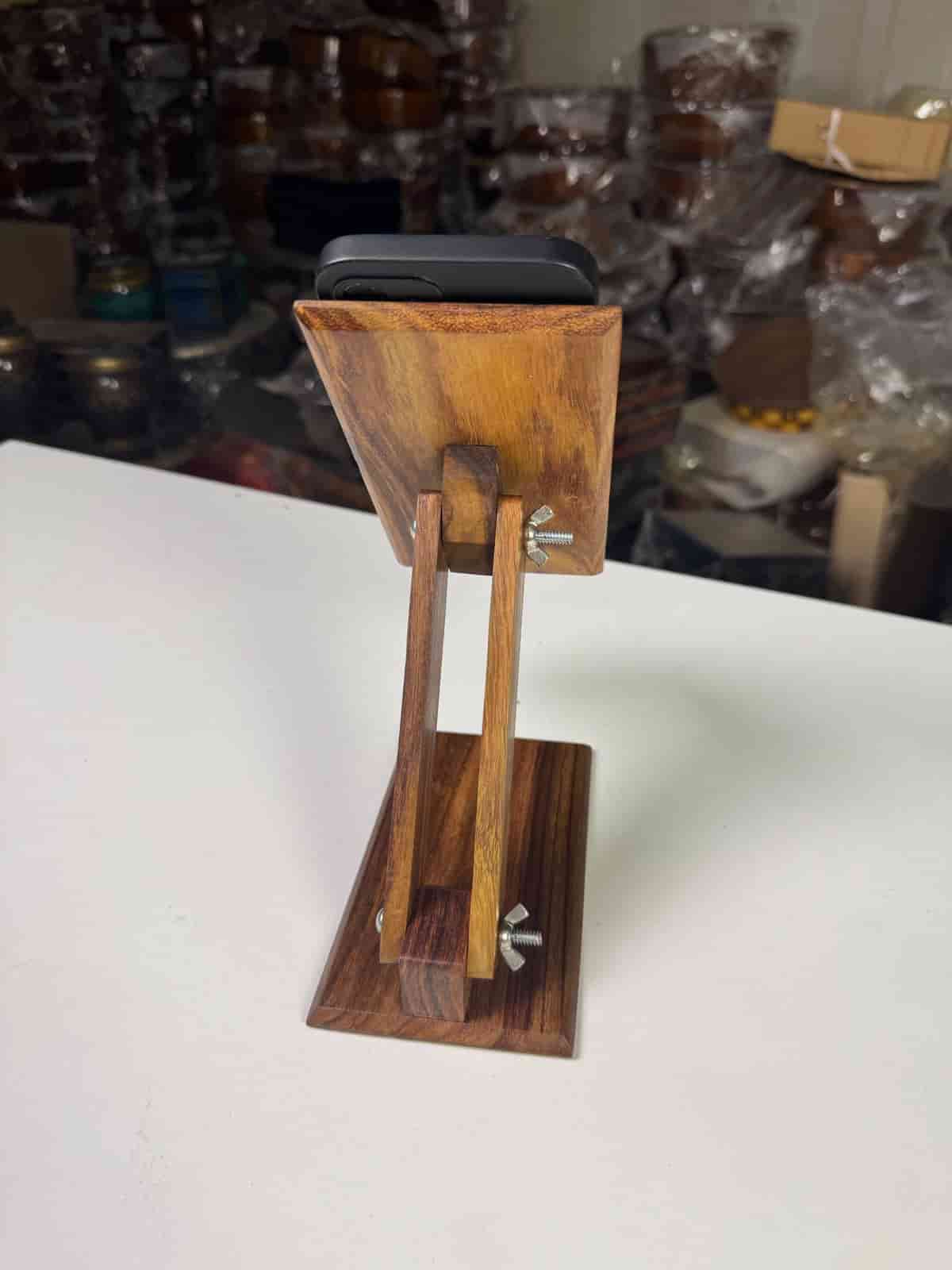 Handcrafted wooden mobile stand holding a smartphone on a desk